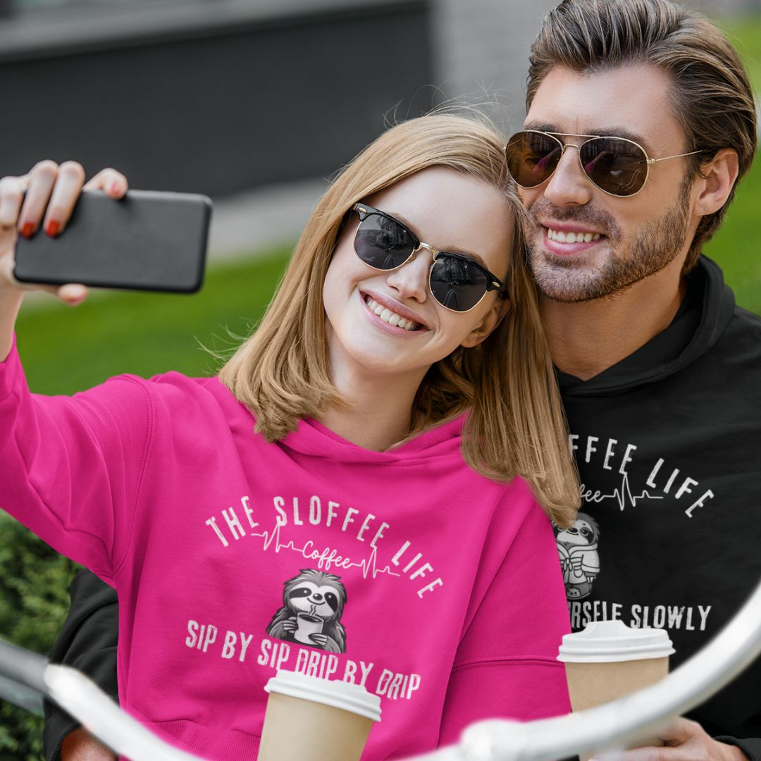 Happy couple taking a selfie, woman wearing a pink Sloffee Life hoodie and man wearing a black Sloffee Life hoodie