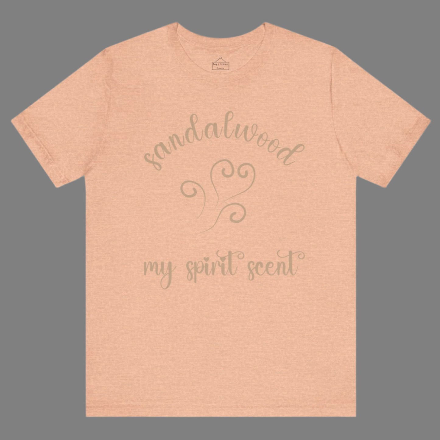 The My Spirit Scent is Sandalwood t-shirt in heather peach featuring script font and an aroma script heart in a warm, muted beige hue