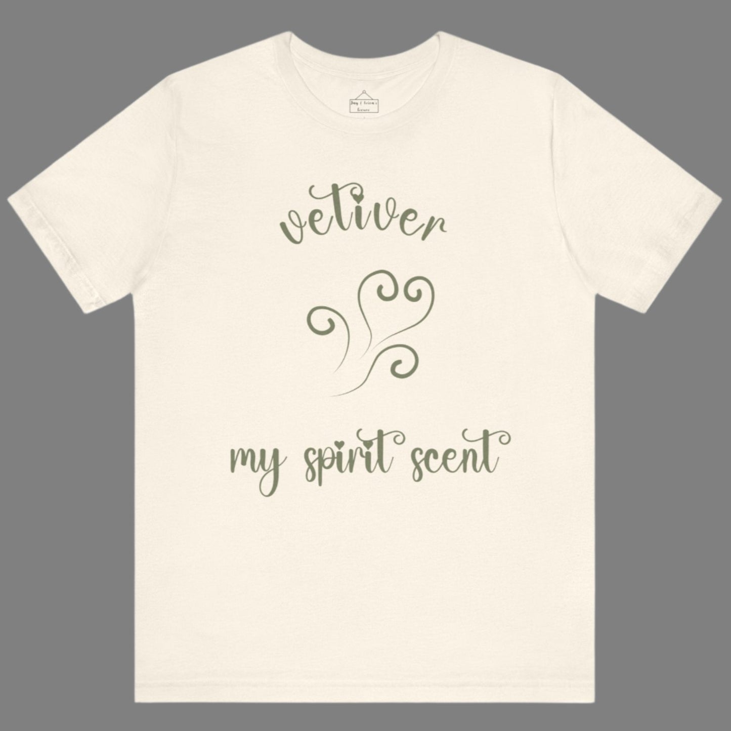 The My Spirit Scent is Vetiver t-shirt in natural featuring script font and an aroma script heart in a grey-green hue