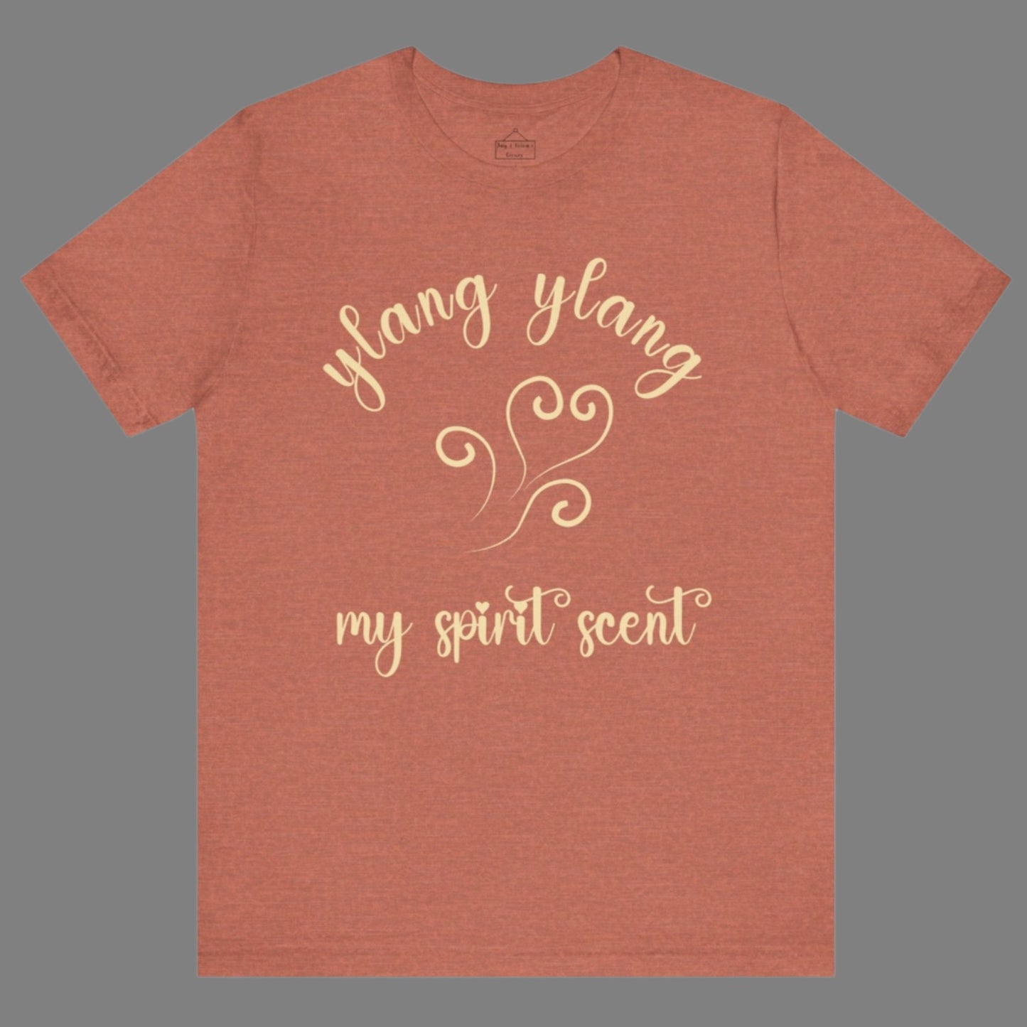 The My Spirit Scent is Ylang Ylang t-shirt in heather clay featuring script font and an aroma script heart in a soft, pastel yellow hue