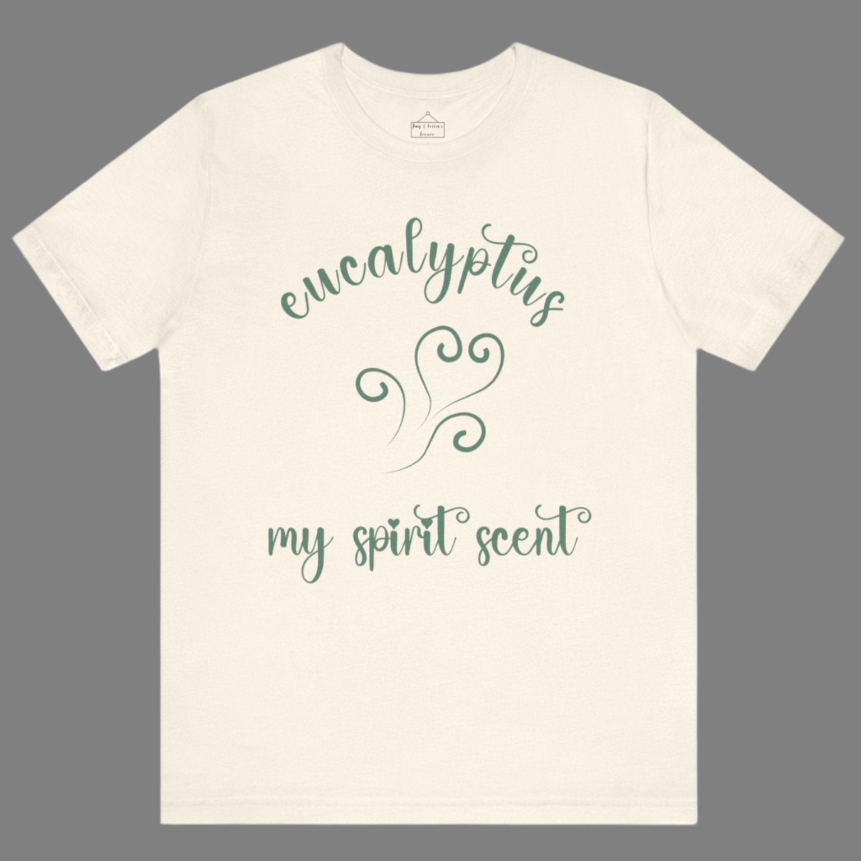 The My Spirit Scent is Eucalyptus t-shirt in natural featuring script font and an aroma script heart in a blue-green hue