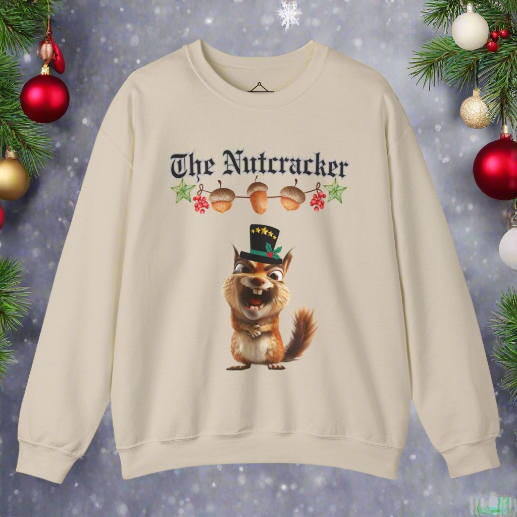 The Nutcracker christmas sweatshirt in sand featuring a strand of acorns hanging above a squirrel making a goofy face wearing a black top hat with a green ribbon and gold stars