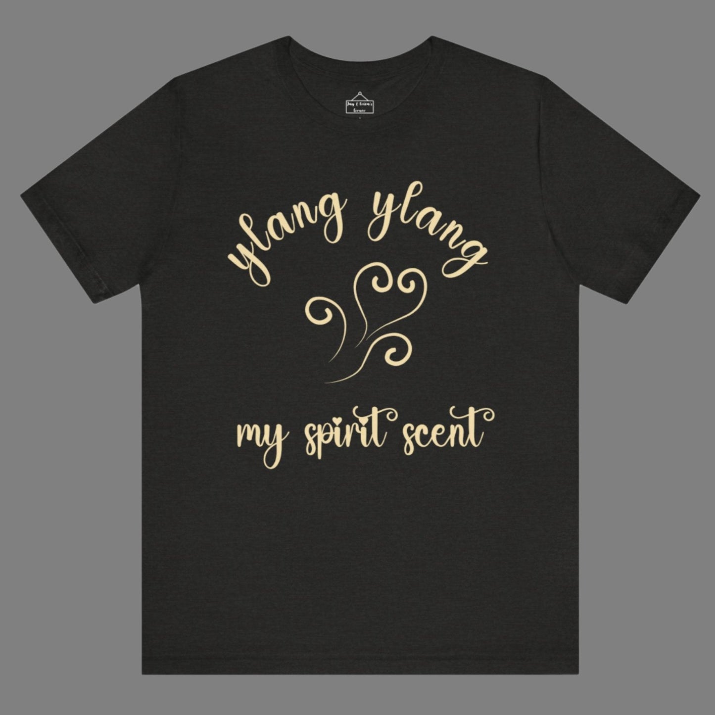 The My Spirit Scent is Ylang Ylang t-shirt in black heather featuring script font and an aroma script heart in a soft, pastel yellow hue