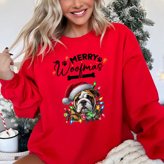 Happy, smiling woman in front of a christmas tree wearing the merry woofmas christmas sweatshirt in red featuring a boxer dog wearing a red hat wrapped in christmas light