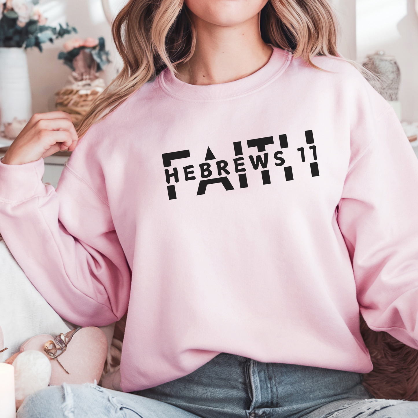 A smiling woman wearing the FAITH Hebrews 11 sweatshirt in light pink featuring the word faith with Hebrews 11 cut between the letters all in black print